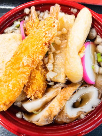 Téléchargez les photos : Plongez dans les saveurs vibrantes de ce bol Tempura Udon, avec tempura de crevettes croustillant, gâteau de poisson et nouilles tendres dans un bouillon salé - en image libre de droit