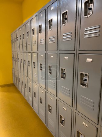 Téléchargez les photos : Dans un couloir scolaire, un ensemble uniforme de casiers gris se tient prêt pour les étudiants, les évents et les serrures ponctuant les portes en métal lisse. - en image libre de droit
