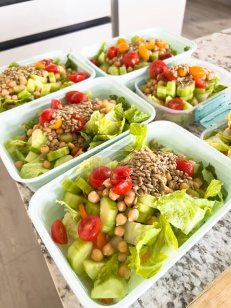 Téléchargez les photos : Des contenants remplis de salades vibrantes et nutritives sont alignés sur un comptoir de cuisine, présentant une façon colorée et saine de se préparer pour les jours de semaine occupés.. - en image libre de droit