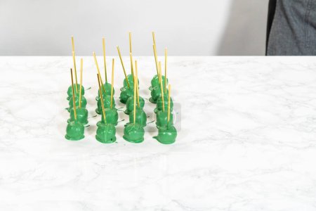 Téléchargez les photos : Tremper des boules de pâte dans du chocolat fondu vert pour faire éclater le gâteau au cactus pour la célébration du Cinco de Mayo. - en image libre de droit