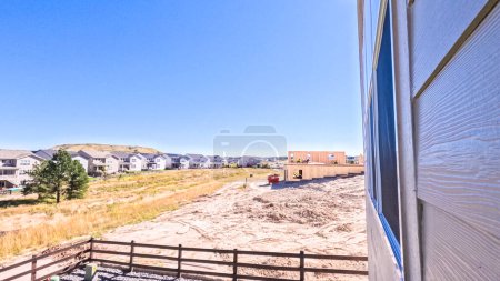 Foto de Denver, Colorado, Estados Unidos-30 de agosto de 2023-El nuevo vecindario residencial revela el marcado contraste entre el marco de madera en bruto de un edificio en construcción y las casas terminadas en el fondo - Imagen libre de derechos