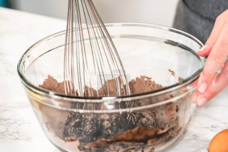 Téléchargez les photos : Dans le processus de création de cupcakes au chocolat appétissants, la première étape consiste à mélanger méticuleusement les ingrédients dans un bol de mélange en verre pour faire la pâte parfaite. - en image libre de droit