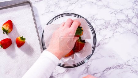 Photo for Flat lay. Strawberries, freshly washed and dried, are neatly stored in a glass bowl lined with a paper towel and securely covered with plastic wrap to maintain freshness. - Royalty Free Image