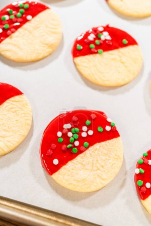 Photo for Skillfully decorating cookies with vibrant red melted chocolate and a generous sprinkle of vibrant green, creating a festive holiday treat. - Royalty Free Image
