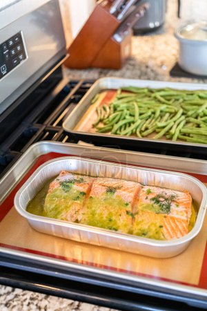 Photo for Discover the mouthwatering journey of salmon as its cooked to perfection in an oven, nestled in a foil tray, adorned with rich butter and tantalizing spices. - Royalty Free Image