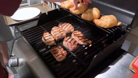 Côtelettes de porc frais sont ornés du mélange parfait d'assaisonnement comme ils cuisinent à la perfection, avec des notes de marques de saisir doré de la chaleur d'un barbecue à gaz extérieur.
