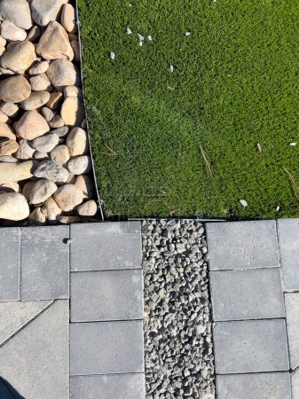 The modern landscaping design features vibrant artificial turf contrasting with natural pebbles and structured pavers, offering a low-maintenance yet aesthetically pleasing outdoor space.