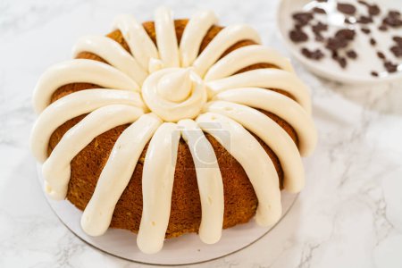 Photo for Icing the pumpkin bundt cake with cream cheese frosting and decorating it with chocolate leaves. - Royalty Free Image