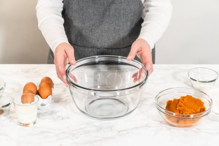 Photo for In a cozy kitchen, a large mixing bowl becomes the stage for expertly blending the ingredients, setting the scene for crafting a delightful homemade pumpkin bundt cake from cake mix. - Royalty Free Image