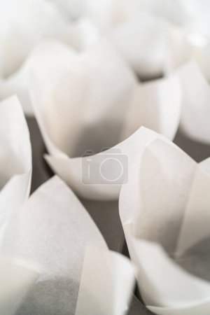Lining baking cupcake pan with paper tulip liners to bake no-yeast cinnamon roll cupcakes.