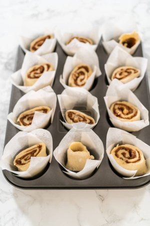 Filling cupcake liners with small cinnamon rolls to bake no-yeast cinnamon roll cupcakes.