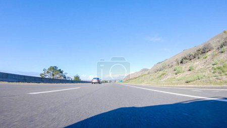 Photo for Santa Maria, California, USA-December 6, 2022-On a crisp winter day, a car cruises along the iconic Highway 1 near San Luis Obispo, California. The surrounding landscape is brownish and subdued, with - Royalty Free Image