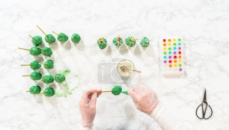 Photo for Flat lay. Decorating cactus cake pops with luster dust, sugar glower, and white sprinkles for the Cinco de Mayo celebration. - Royalty Free Image