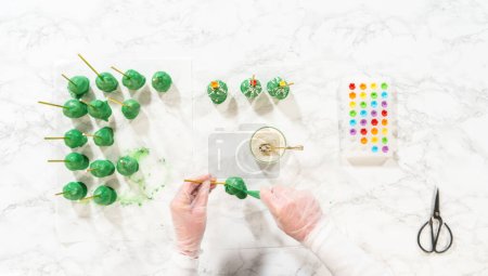 Photo for Flat lay. Decorating cactus cake pops with luster dust, sugar glower, and white sprinkles for the Cinco de Mayo celebration. - Royalty Free Image