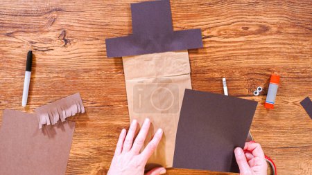 Téléchargez les photos : Pas à pas. Pose plate. L'enseignant guide la classe en ligne en fabriquant une marionnette en papier à partir d'un sac brun, en utilisant de manière créative une surface en bois comme espace de travail. - en image libre de droit