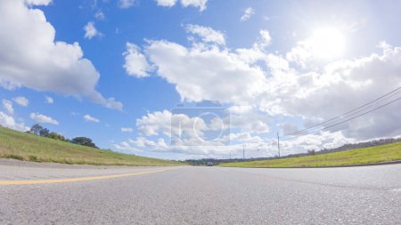 Photo for On a clear winter day, a car smoothly travels along Highway 101 near Santa Maria, California, under a brilliant blue sky, surrounded by a blend of greenery and golden hues. - Royalty Free Image