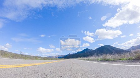 Fahrzeug cruist auf dem Cuyama Highway in der strahlenden Sonne. Die umliegende Landschaft wird von der strahlenden Sonne erhellt und schafft eine malerische und einladende Szenerie, während das Auto unterwegs ist
