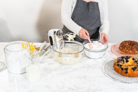 Téléchargez les photos : Combinez habilement les ingrédients à l'aide d'un mélangeur à main pour préparer un glaçage riche et lisse au fromage à la crème au beurre, parfait pour orner le gâteau bundt. - en image libre de droit