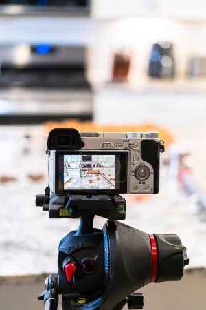 A DSLR camera, set up in a sleek, modern kitchen, captures the making of a video recipe for vlogging.