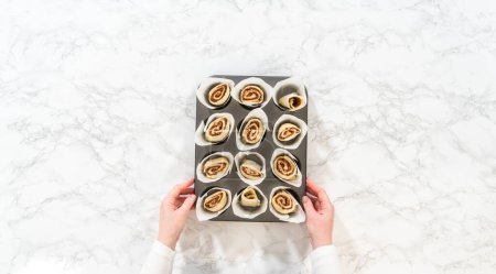 Photo for Flat lay. Filling cupcake liners with small cinnamon rolls to bake no-yeast cinnamon roll cupcakes. - Royalty Free Image