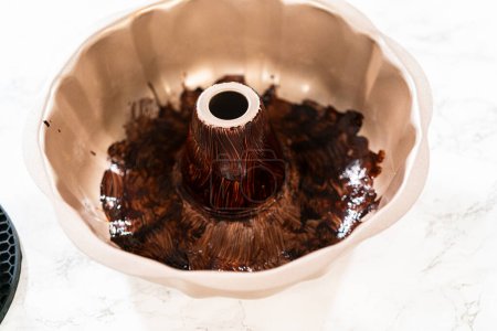 Preparing the bundt cake pan for baking, a mixture of melted vegetable shortening and cocoa powder is skillfully applied to ensure easy release and a beautifully baked bundt cake.