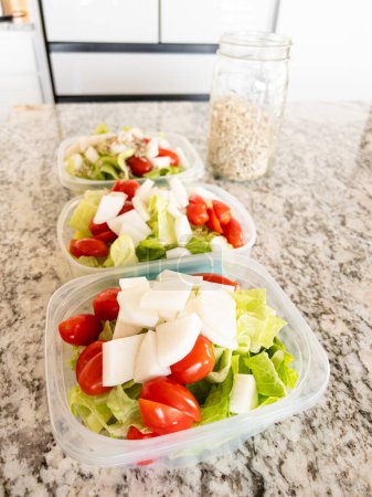 Foto de Envases llenos de ensalada y aderezo, preparados para la preparación conveniente de la comida a la hora del almuerzo. - Imagen libre de derechos