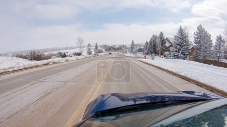 Téléchargez les photos : En traversant une route de banlieue fraîchement dégagée après une tempête hivernale, on fait l'expérience d'un trajet serein à travers un quartier résidentiel haut de gamme. Maisons couvertes de neige et les arbres contribuent à un pittoresque - en image libre de droit