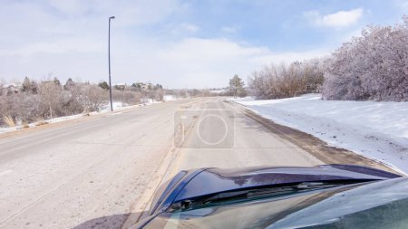 Photo for Traversing a freshly cleared, suburban road after a winter storm, one experiences a serene drive through an upscale residential neighborhood. Snow-covered houses and trees contribute to a picturesque - Royalty Free Image