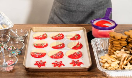 Téléchargez les photos : Biscuits rouge vif en forme d'étoile, généreusement glacés et parsemés de saupoudres de vacances vertes et blanches, fraîchement préparés et disposés pour sécher. - en image libre de droit