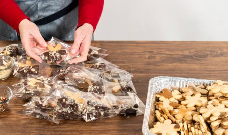 Téléchargez les photos : Emballage soigné des biscuits de Noël découpés, à moitié trempés dans du chocolat et présentés dans un emballage en cellophane transparent, parfait pour les cadeaux festifs. - en image libre de droit