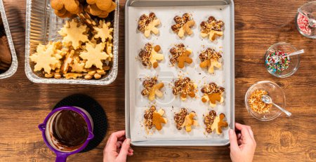 Photo for Gingerbread men cookies, chocolate-dipped feet, generously sprinkled with golden toasted coconut shavings, artfully arranged on parchment paper. - Royalty Free Image