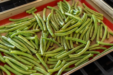Watch as fresh green beans are beautifully roasted to perfection on a baking sheet with a silicone mat, adding a burst of flavor to your meal.
