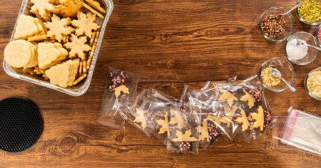 Téléchargez les photos : Emballage soigné des biscuits de Noël découpés, à moitié trempés dans du chocolat et présentés dans un emballage en cellophane transparent, parfait pour les cadeaux festifs. - en image libre de droit