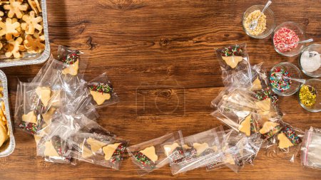 Carefully packaging Christmas cutout cookies, half-dipped in chocolate and presented in clear cellophane wrapping, perfect for festive gifting.