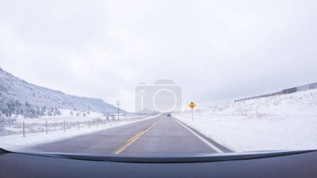 The open highway invites a peaceful drive, with snow-clad pines lining I-25 as the journey continues from Denver towards Colorado Springs on a snowy day.