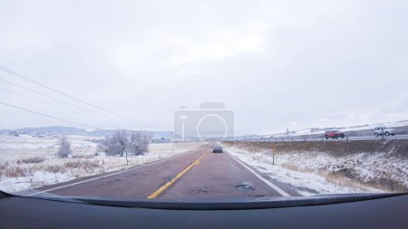 Foto de La carretera abierta invita a un paseo tranquilo, con pinos nevados alineando la I-25 mientras el viaje continúa desde Denver hacia Colorado Springs en un día nevado. - Imagen libre de derechos