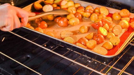 En el marco de una cocina moderna, un joven se sumerge en la preparación de la cena, actualmente asando patatas arcoiris sazonadas en el horno, un paso importante hacia una deliciosa comida.