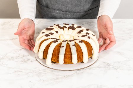 Téléchargez les photos : Glaçage du gâteau bundt à la citrouille avec glaçage au fromage à la crème et décorer avec des feuilles de chocolat. - en image libre de droit