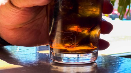 Foto de Un primer plano muestra un refrescante vaso lleno de cubitos de hielo y refrescos, colocado en una mesa de restaurante, invitando al espectador a disfrutar de una bebida fresca y gaseosa. - Imagen libre de derechos