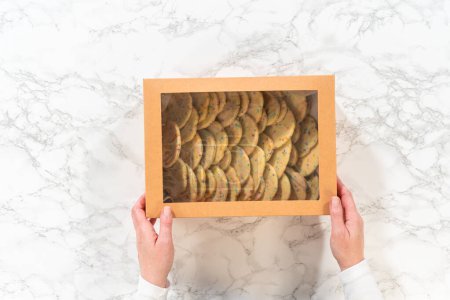 Photo for Flat lay. The sugar cookies, filled with sprinkles mixed into the dough, are carefully arranged with meticulous precision into a rustic brown paper box. - Royalty Free Image