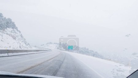Foto de El vehículo POV-Electric es capturado hábilmente navegando por la carretera I-70 durante una tormenta de invierno en el oeste de Colorado. - Imagen libre de derechos