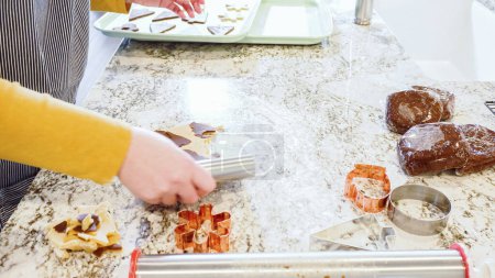À l'aide de diverses coupeuses festives, découpaient de charmants biscuits au pain d'épice de la pâte roulée sur le comptoir en marbre élégant, apportant joie de vacances à la cuisine moderne.