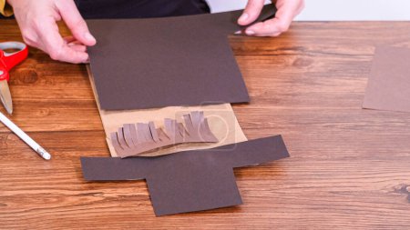 Téléchargez les photos : Pas à pas. L'enseignant guide la classe en ligne en fabriquant une marionnette en papier à partir d'un sac brun, en utilisant de manière créative une surface en bois comme espace de travail. - en image libre de droit