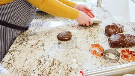 Utilisation d'un rouleau à pâtisserie réglable pour dérouler la pâte à biscuits au pain d'épice sur l'élégant comptoir en marbre dans une cuisine moderne, se préparer pour la cuisson de vacances festives.