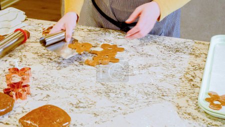 Photo for Using various festive cookie cutters, were cutting out charming gingerbread cookies from the rolled dough on the sleek marble counter, bringing holiday cheer to the modern kitchen. - Royalty Free Image