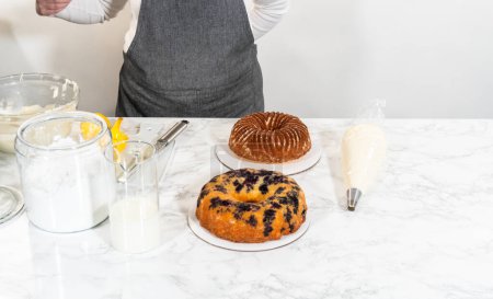 Photo for The final stage of this delightful baking journey involves artistically piping the silky cream cheese buttercream frosting atop the cooled bundt cakes, creating an irresistible treat. - Royalty Free Image