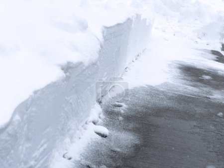 Foto de Una pasarela limpiamente paleada corta una gruesa capa de nieve, revelando un marcado contraste contra una barrera blanca prístina. - Imagen libre de derechos
