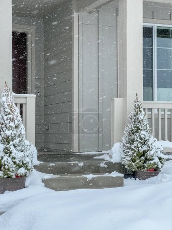 Téléchargez les photos : Des flocons de neige doux descendent sur une entrée accueillante de la maison, festoient les épinettes et recouvrent le porche d'une couche douce et hivernale. - en image libre de droit