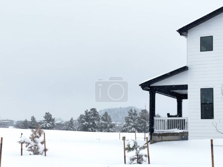 Téléchargez les photos : Le contraste saisissant d'une maison moderne vêtue de blanc dans un décor enneigé discret évoque un sentiment de confort isolé dans le froid de l'hiver. - en image libre de droit