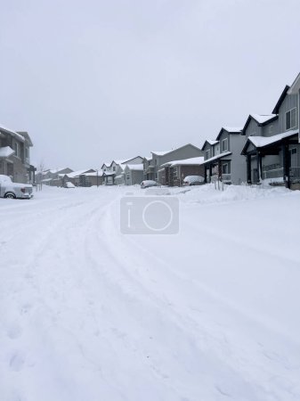 Téléchargez les photos : Castle Rock, Colorado, États-Unis-16 mars 2024-La scène représente une tranquillité suburbaine avec des maisons bordant une rue recouverte de neige, ponctuées d'un sentier dégagé qui traverse le pays des merveilles hivernales - en image libre de droit